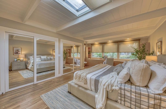 bedroom with a skylight, hardwood / wood-style floors, and beamed ceiling