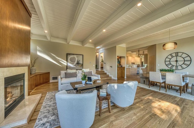 living room featuring beam ceiling, a high end fireplace, wood walls, and hardwood / wood-style flooring