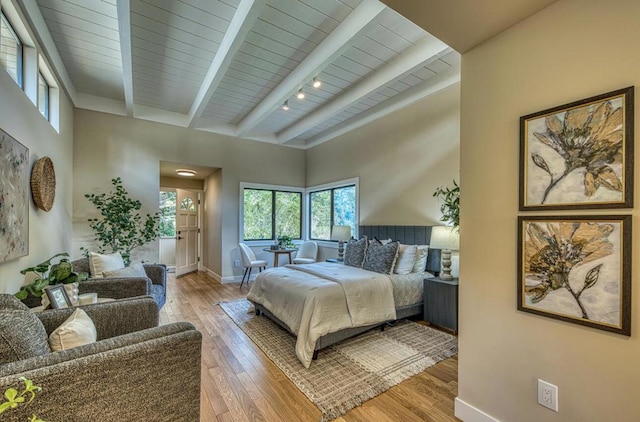 bedroom featuring a high ceiling, beam ceiling, and light hardwood / wood-style flooring