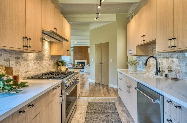 kitchen featuring light stone countertops, track lighting, light brown cabinets, stainless steel appliances, and sink