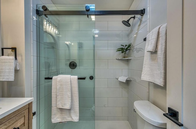 bathroom with toilet, vanity, and a shower with door