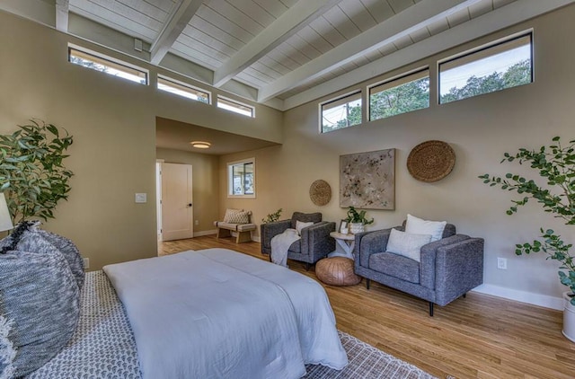 bedroom with a towering ceiling, light hardwood / wood-style flooring, and beamed ceiling