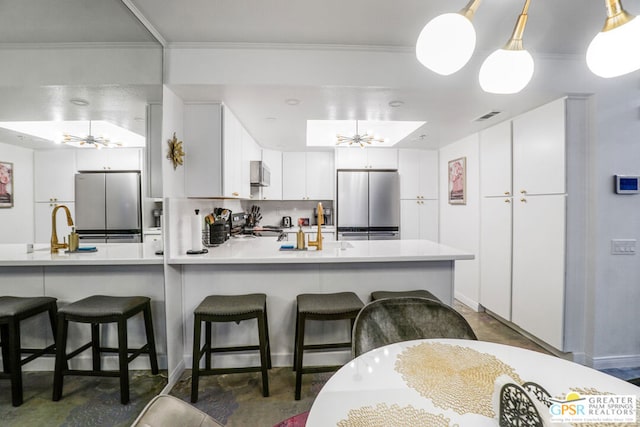 kitchen with stainless steel refrigerator, ceiling fan, kitchen peninsula, and white cabinets