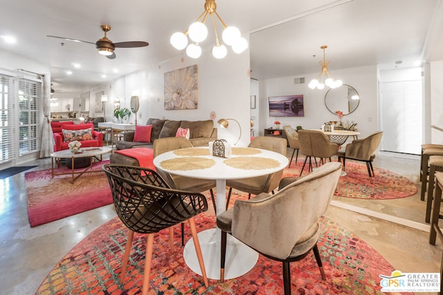 dining area featuring concrete flooring and ceiling fan with notable chandelier