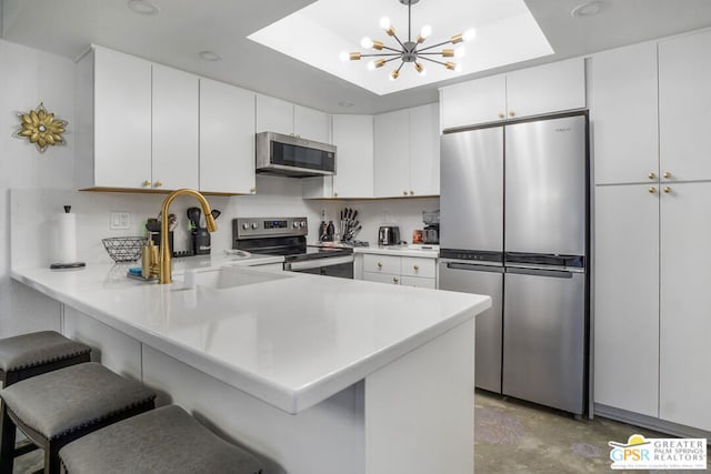 kitchen featuring stainless steel appliances, white cabinets, a kitchen breakfast bar, and kitchen peninsula