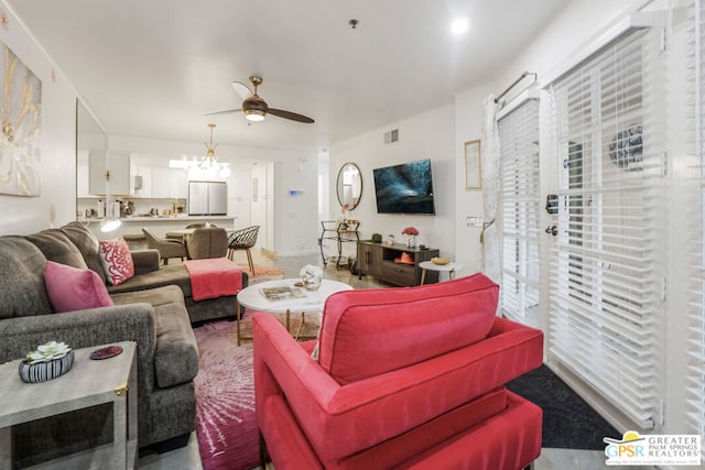 living room with ceiling fan with notable chandelier