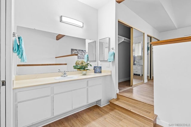 bathroom with hardwood / wood-style flooring, vanity, and beam ceiling