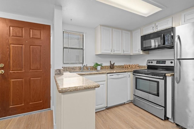 kitchen with white cabinetry, light hardwood / wood-style floors, stainless steel appliances, light stone countertops, and sink