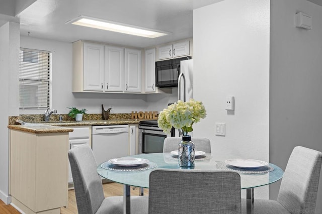 kitchen with white dishwasher, white cabinets, stainless steel stove, light hardwood / wood-style flooring, and sink