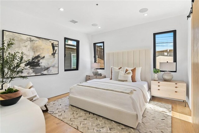 bedroom with light hardwood / wood-style floors and multiple windows