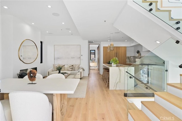 kitchen with light hardwood / wood-style floors, decorative light fixtures, a large island, and a breakfast bar area