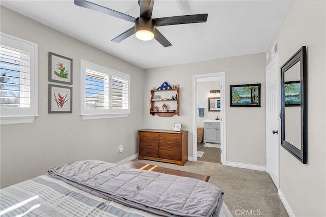 carpeted bedroom featuring ceiling fan, multiple windows, and ensuite bathroom