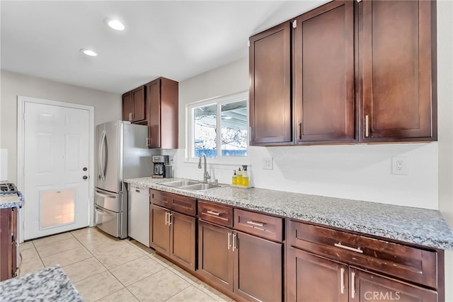 kitchen with dark brown cabinetry, stainless steel appliances, sink, light stone counters, and light tile patterned floors