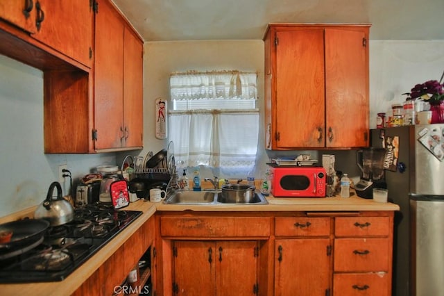 kitchen with black gas cooktop, stainless steel fridge, and sink