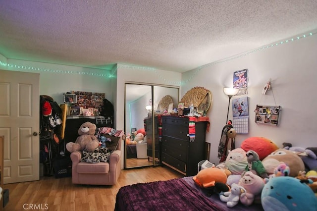 bedroom with a textured ceiling, a closet, and light hardwood / wood-style floors