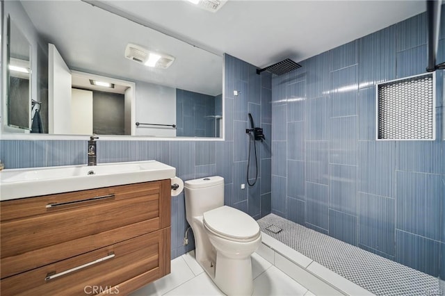 bathroom with tile patterned flooring, vanity, tile walls, toilet, and tiled shower