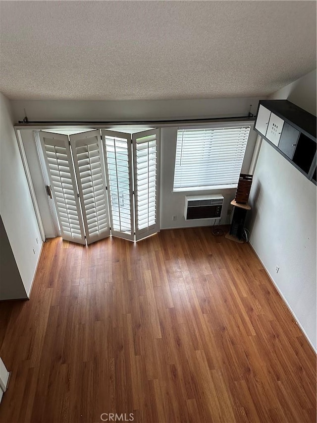 623 N Bristol St Unit 79, Santa Ana, CA 92703 - unfurnished living room featuring a wall unit AC, wood finished floors, and a textured ceiling