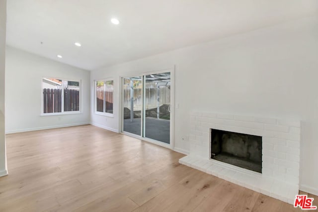 unfurnished living room with vaulted ceiling, light hardwood / wood-style flooring, and a fireplace