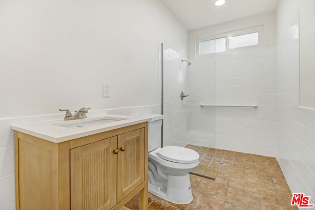 bathroom featuring toilet, vanity, and a tile shower