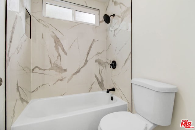 bathroom featuring tiled shower / bath combo and toilet