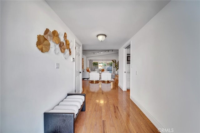 hallway featuring vaulted ceiling and wood-type flooring