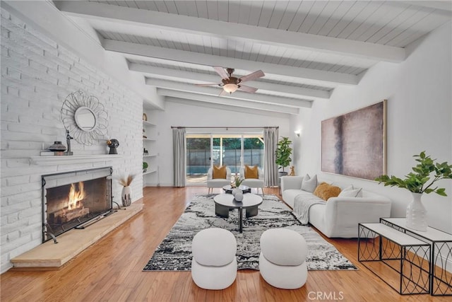 living room with a fireplace, hardwood / wood-style flooring, ceiling fan, and vaulted ceiling with beams