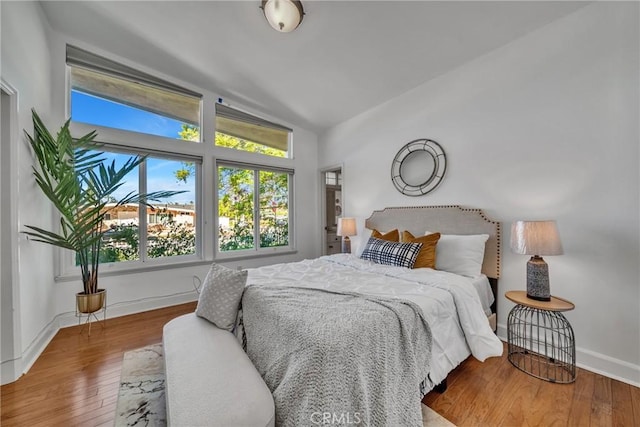 bedroom with wood-type flooring and vaulted ceiling