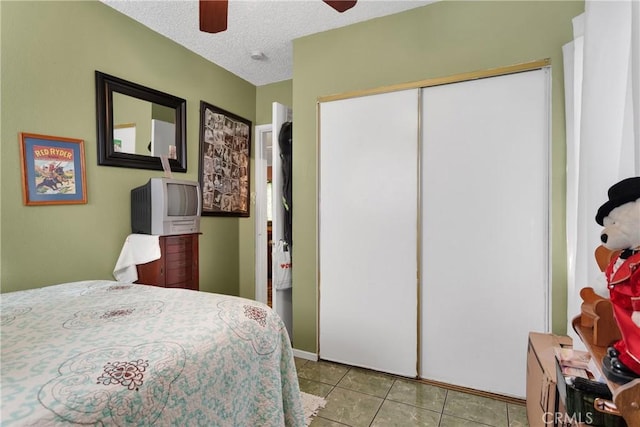 bedroom featuring ceiling fan, a textured ceiling, a closet, and light tile patterned flooring