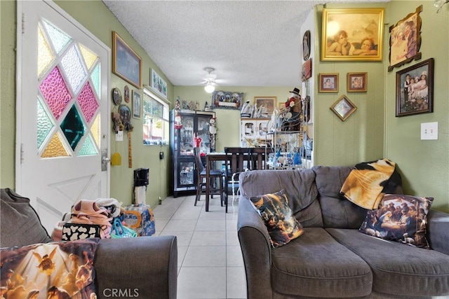 living room with ceiling fan, light tile patterned floors, and a textured ceiling