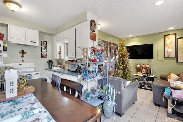 kitchen with light tile patterned flooring, white cabinetry, a textured ceiling, and white range with electric cooktop