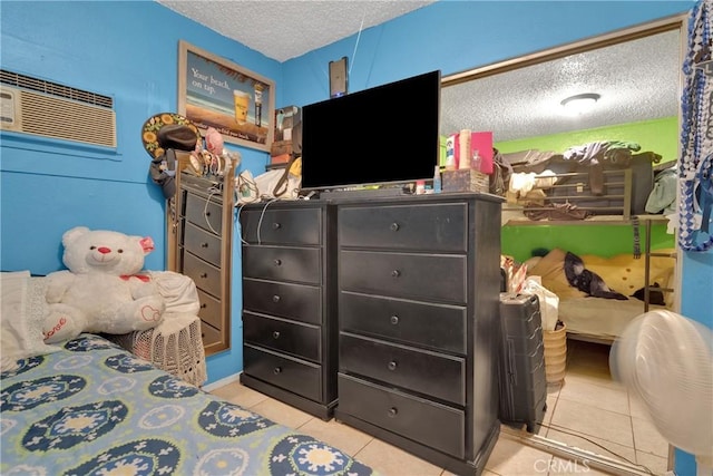 bedroom featuring a textured ceiling, light tile patterned floors, and a wall unit AC