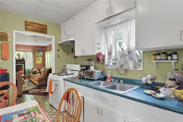 kitchen featuring light tile patterned floors, sink, white gas stove, and white cabinetry