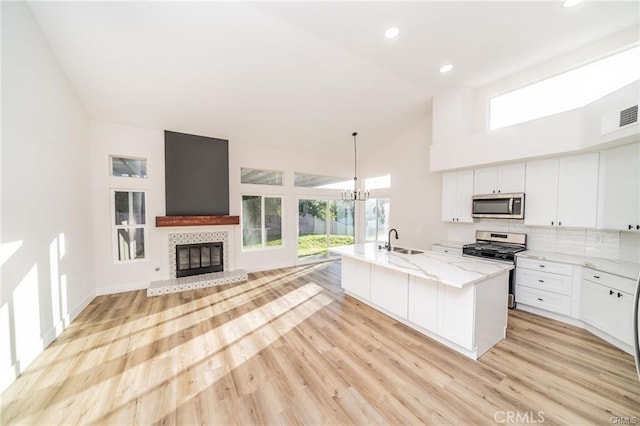 kitchen with stainless steel appliances, white cabinets, a center island with sink, and sink