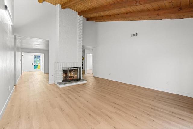 unfurnished living room featuring wood ceiling, beamed ceiling, a fireplace, high vaulted ceiling, and light hardwood / wood-style flooring