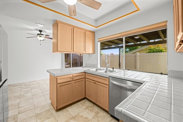 kitchen featuring tile countertops, kitchen peninsula, ceiling fan, dishwasher, and sink