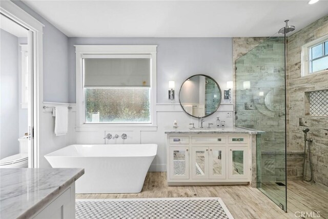 bathroom with vanity, wood-type flooring, and plus walk in shower