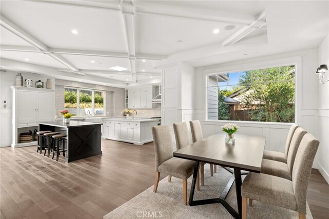 dining area featuring hardwood / wood-style flooring, beam ceiling, and coffered ceiling