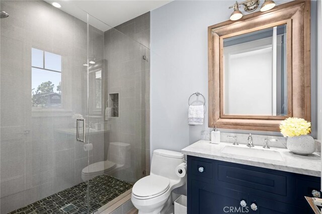 bathroom with toilet, vanity, and an enclosed shower