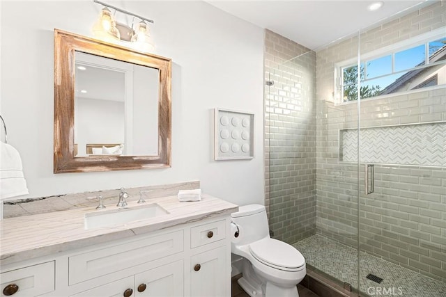 bathroom featuring vanity, an enclosed shower, and toilet