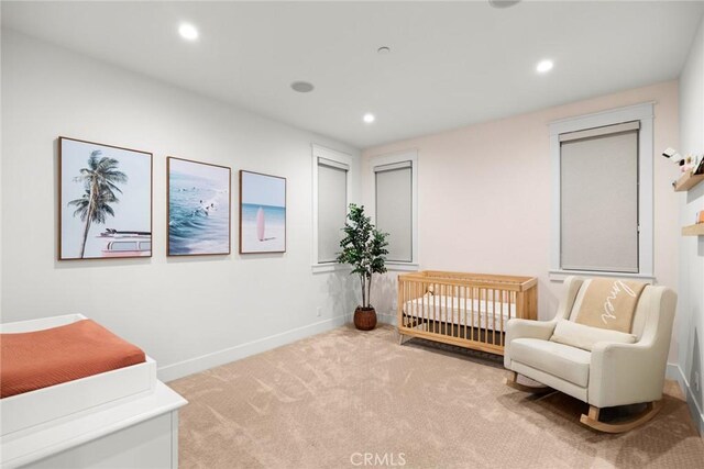 bedroom featuring light colored carpet and a crib