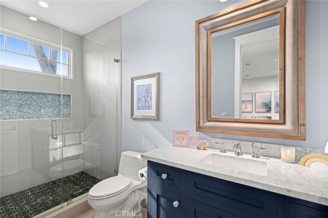 bathroom with vanity, a shower with door, and toilet