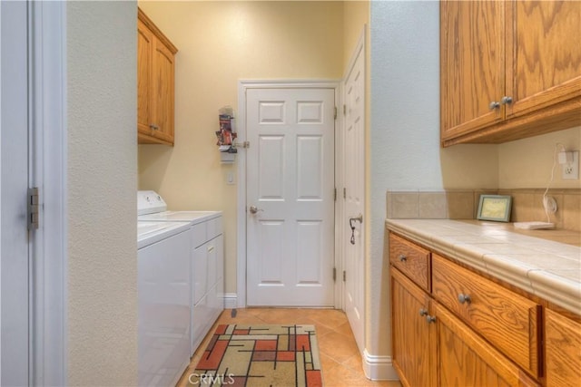 laundry room featuring cabinets, light tile patterned floors, and independent washer and dryer