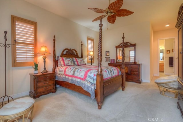 bedroom featuring ensuite bath, light colored carpet, and ceiling fan