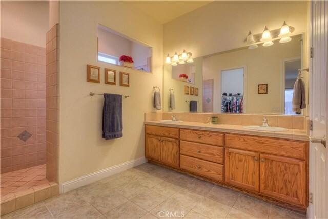 bathroom featuring a tile shower, tile patterned floors, and vanity