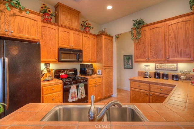 kitchen with sink, black appliances, and tile counters