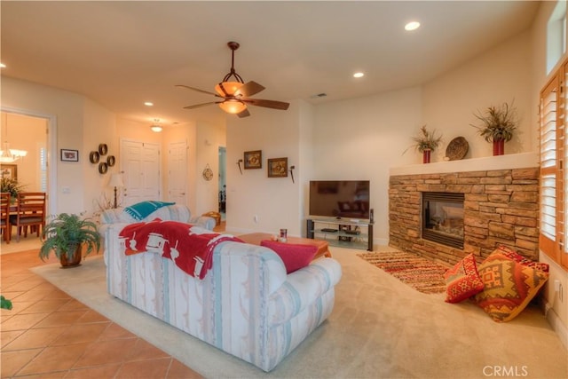 living room with a fireplace, light tile patterned flooring, and ceiling fan with notable chandelier