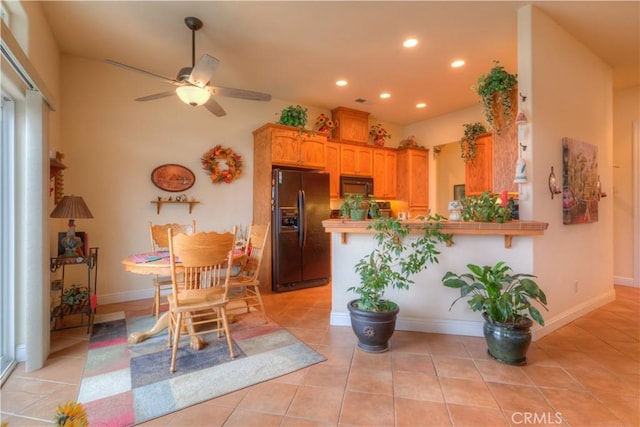 kitchen with light tile patterned floors, kitchen peninsula, ceiling fan, black refrigerator with ice dispenser, and a breakfast bar