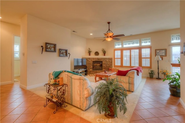 tiled living room with ceiling fan and a stone fireplace