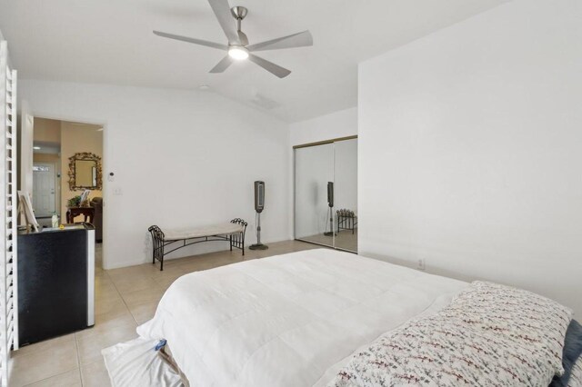 bedroom with ceiling fan, light tile patterned floors, a closet, and lofted ceiling