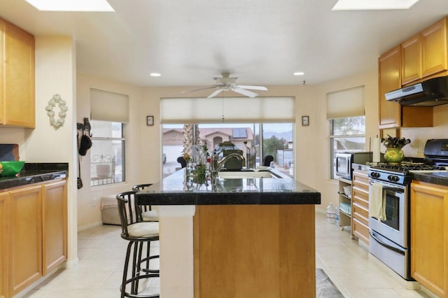 kitchen featuring stainless steel appliances, sink, ceiling fan, a center island with sink, and a breakfast bar area